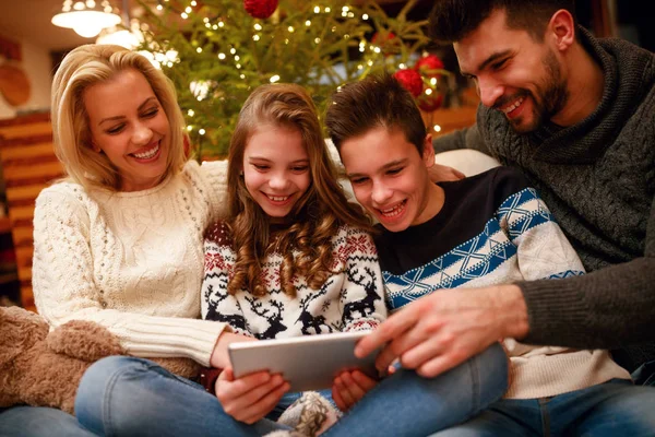 Улыбающаяся семья веселится на цифровом планшете на Рождество — стоковое фото