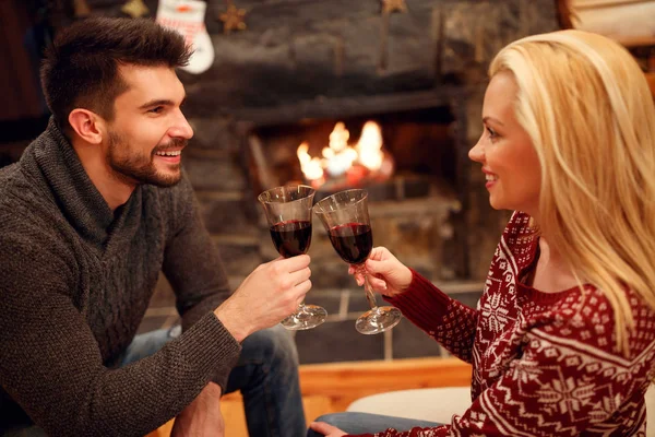 Женщина и мужчина пьют восхитительное красное вино у романтического камина — стоковое фото
