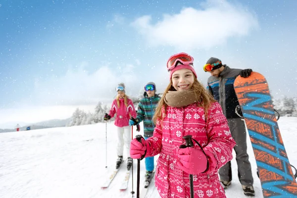 Chica sonriente con la familia en terreno de esquí —  Fotos de Stock