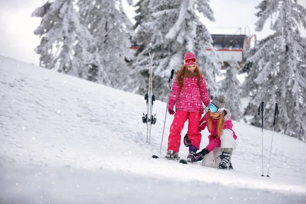 Heure d'hiver et ski - mère préparant sa fille sur la station de ski — Photo