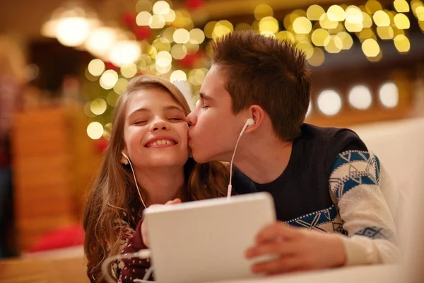 Child's with headphones lying and using a tablet - brother kiss — Stock Photo, Image
