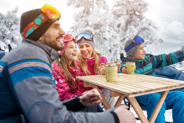 Familia riendo y toma un descanso para tomar el té durante el esquí en la montaña — Foto de Stock