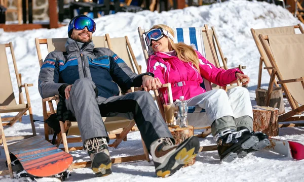 Casal em montanhas no inverno rindo e relaxar na cama de sol — Fotografia de Stock