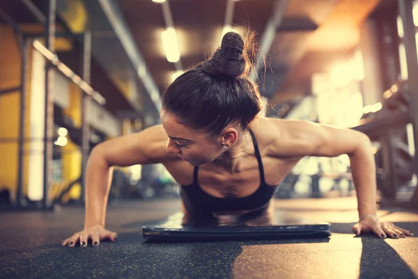 Mujer en el gimnasio poniendo los brazos en la posición adecuada para el ejercicio de flexiones —  Fotos de Stock