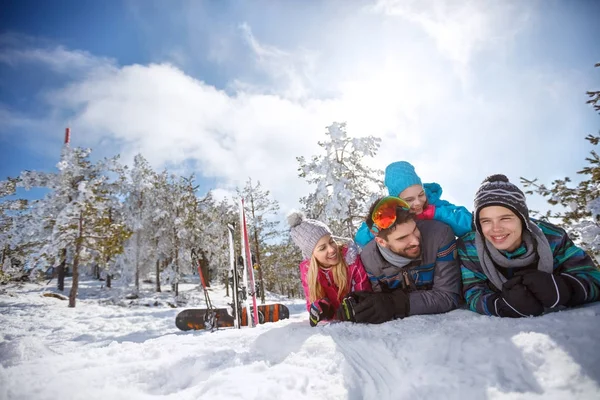 Lyžaři rodina leží na sněhu na zimní dovolenou — Stock fotografie
