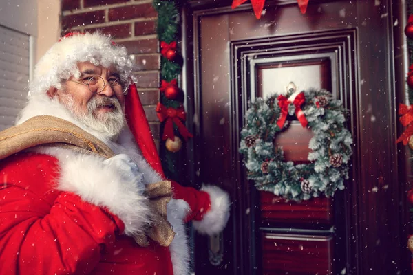 Санта-Клаус с мешком перед рождественской дверью — стоковое фото