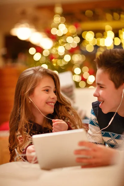 Niños con auriculares acostados y usando una tableta y sonriendo —  Fotos de Stock