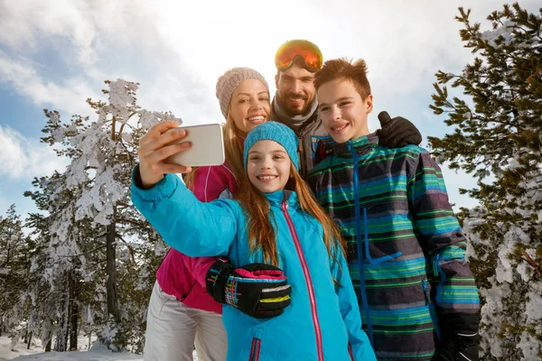 Family laughing and making selfie with smartphone on winter ski vacation — Stock Photo, Image