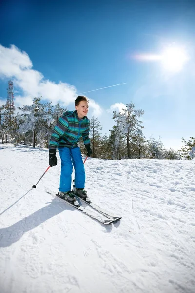 Счастливый маленький мальчик катается на лыжах вниз в солнечный зимний день — стоковое фото