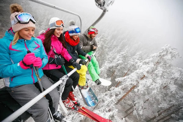 Friends skiers on ski lift ride up on ski slope at snowy day — Stock Photo, Image