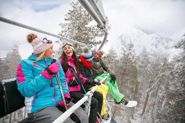 Amigos felices disfrutando en las vacaciones de invierno. Suben a un telesilla — Foto de Stock