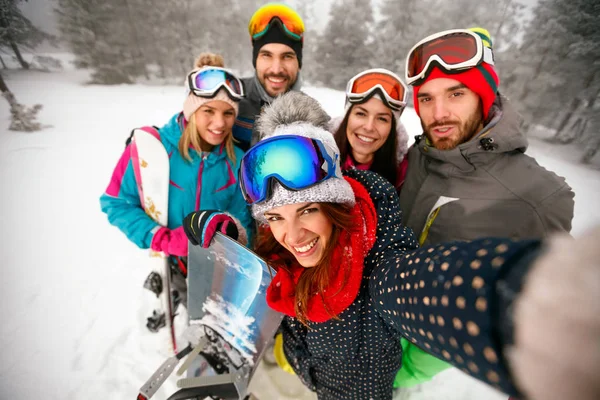 Улыбающиеся друзья веселятся в зимние каникулы. Сноубордисты и лыжники — стоковое фото