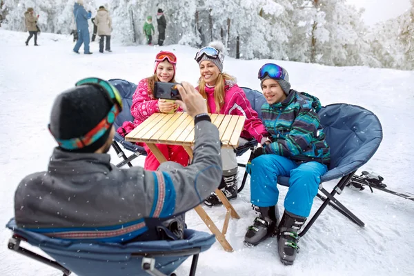 Pai fazendo foto de sua família no café no terreno de esqui — Fotografia de Stock