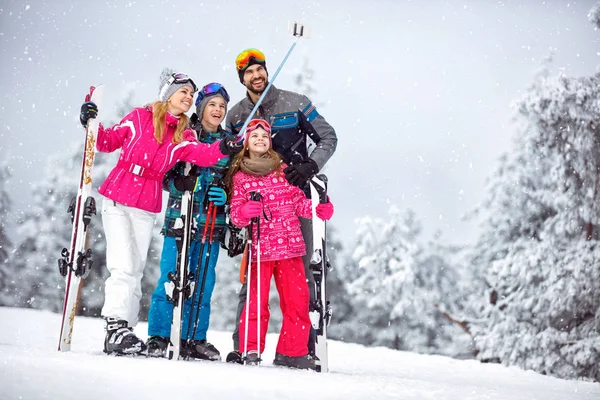Familia haciendo selfie juntos en la montaña nevada — Foto de Stock