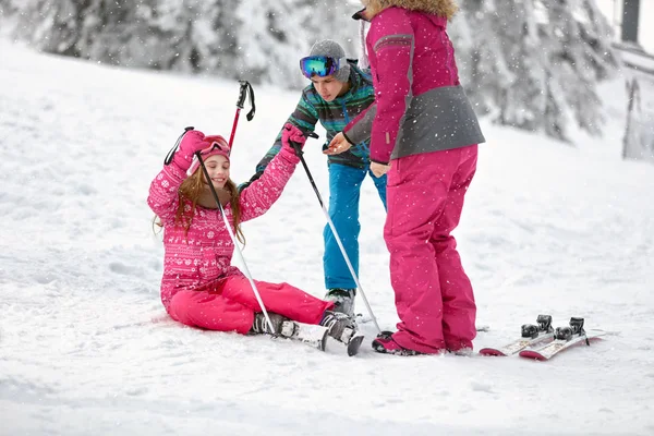 Madre e fratello impara la ragazza ad alzarsi dalla neve con gli sci — Foto Stock