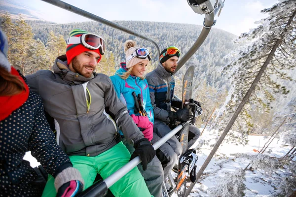 Mannelijke en vrouwelijke skiërs opheffend op ski terrein met skilift — Stockfoto