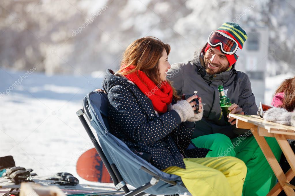 Skiers couple drinking and talking in cafe on skiing