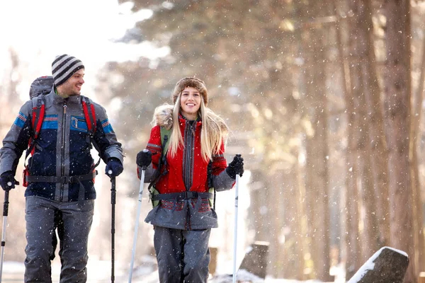 男性と女性のハイカーが雪に覆われた自然の中歩いて — ストック写真