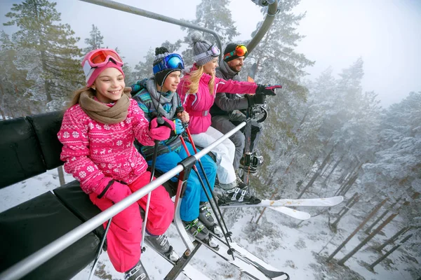 Šťastná rodina lyžaři na lyžařský vlek na horu — Stock fotografie