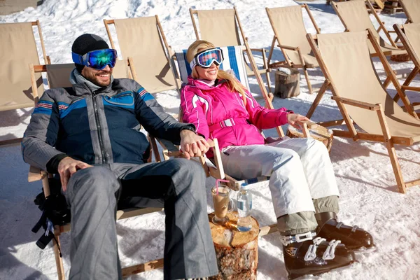 Casal rindo e relaxar na cama de sol em montanhas no inverno — Fotografia de Stock