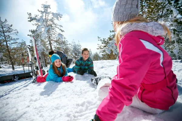 Familia con niños jugando en la nieve en las vacaciones de esquí en las montañas — Foto de Stock