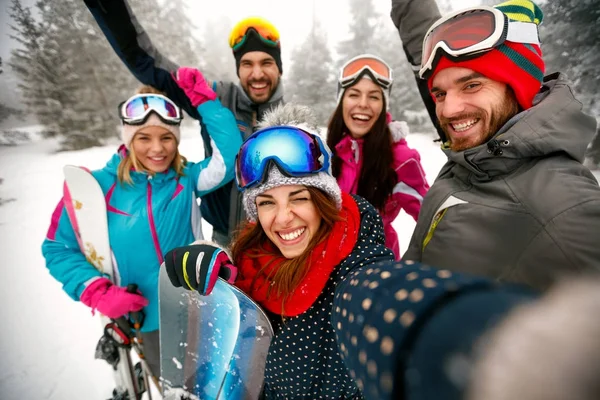 Amigos sonrientes divirtiéndose. Snowboarders y esquiadores haciendo selfie —  Fotos de Stock