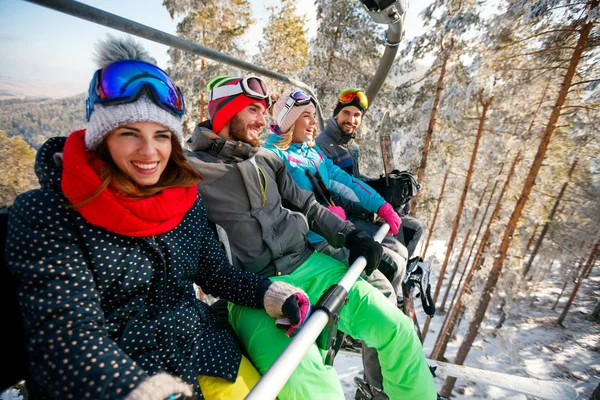 Lachende vrienden skiërs en snowboarders op skilift — Stockfoto