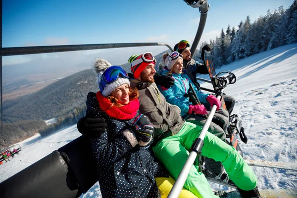 Skiërs en snowboarders genieten op ski lift op zonnige dag — Stockfoto