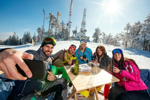 Group of friends laughing and enjoying in drink at ski resort — Stock Photo, Image