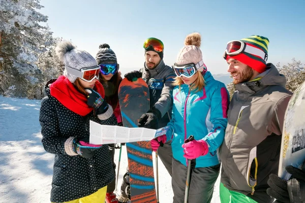 Vrienden lezen van een papieren kaart in wintervakantie in besneeuwde berg — Stockfoto