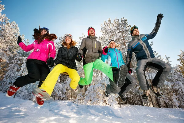 Felices amigos saltando en la nieve —  Fotos de Stock