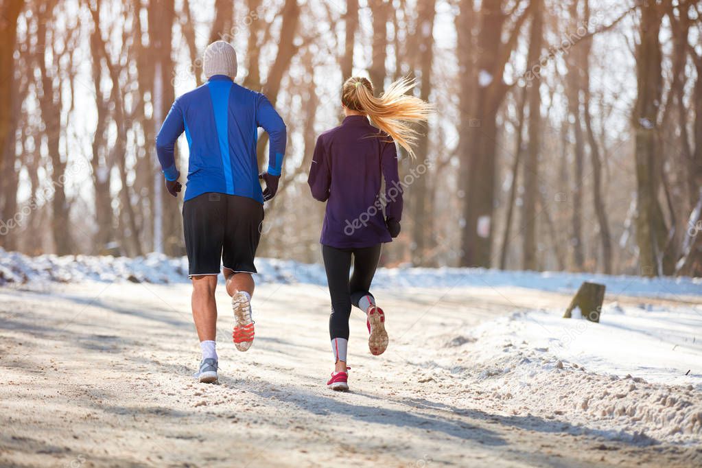 Couple jogging in nature together, back view