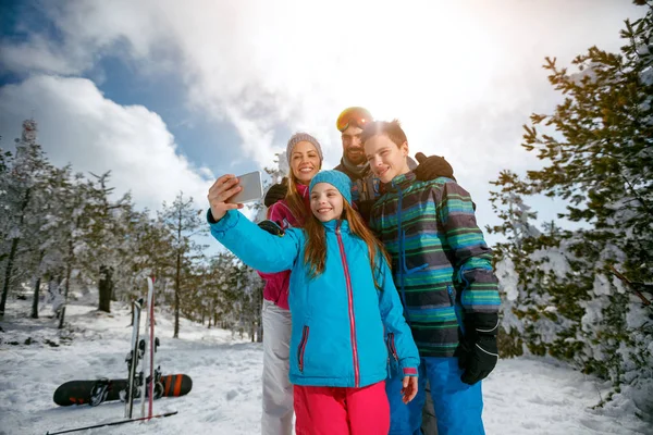 Family laughing and making selfie with mobile on winter ski vacation — Stock Photo, Image