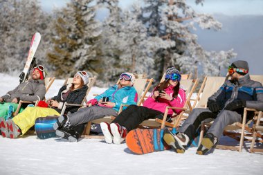 Skiers in sun bad sitting and pausing from skiing clipart
