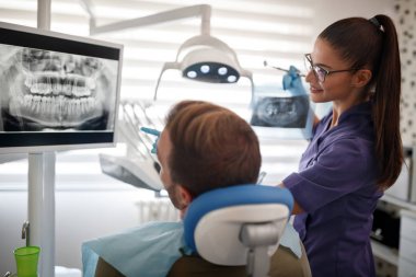 X-ışını hastaya açıklayan diş hekimi 