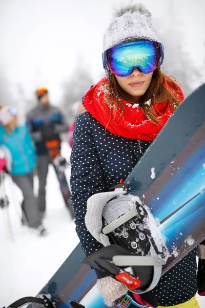 Woman holding snowboard on ski terrain — Stock Photo, Image