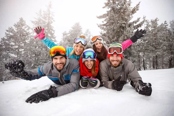 Cheerful friends on skiing laying together on snow — Stock Photo, Image