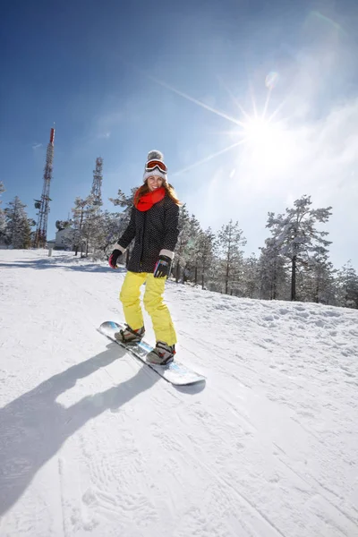 Female snowboarder snowboarding in mountain — Stock Photo, Image