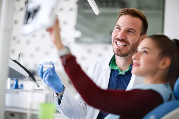 Tandarts en zijn patiënt kijken kaak model — Stockfoto