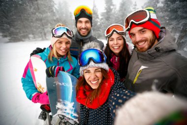 Grup gülümseyen arkadaşıyla birlikte eğlenceli snowboard ve kayakçılar sahip 