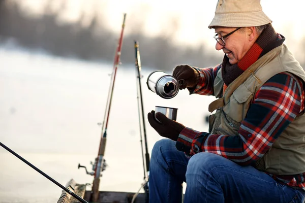 Рыбак пьет горячий чай во время рыбалки с лодки — стоковое фото