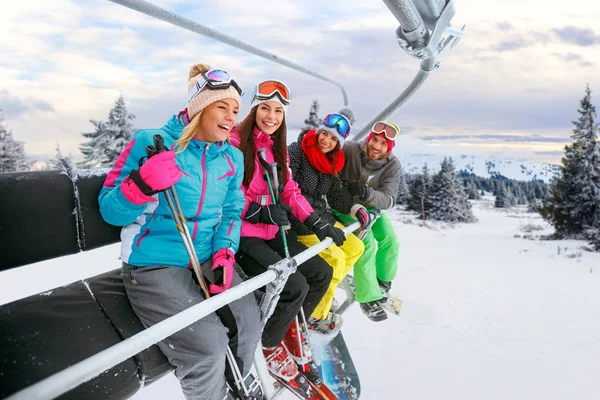 Amigos alegres no elevador de esqui passeio na montanha nevada — Fotografia de Stock