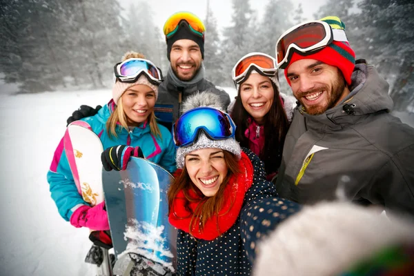 Gruppe lächelnder Freunde, die Spaß an Snowboardern und Skifahrern haben — Stockfoto