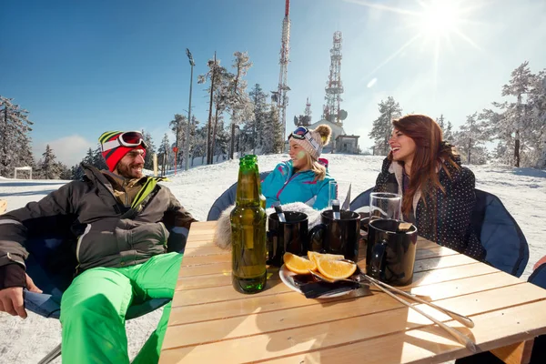 Amigos rindo e desfrutando em bebida na estância de esqui — Fotografia de Stock