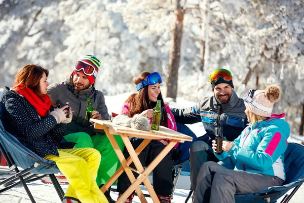 Amigos riendo y tomando un descanso para tomar el té durante el esquí en la montaña — Foto de Stock