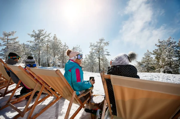Amigos sentados con tumbonas en las montañas de invierno. Vista trasera — Foto de Stock
