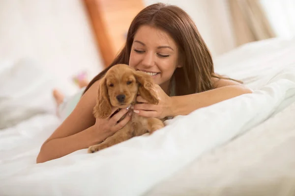 Jong meisje geniet van met haar puppy in slaapkamer — Stockfoto
