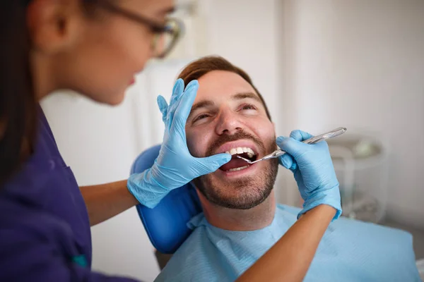 Dentiste vérifiant les dents du patient avec miroir dentaire — Photo