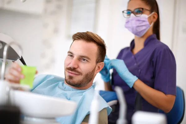 Paciente em dentista tomando copo de água — Fotografia de Stock