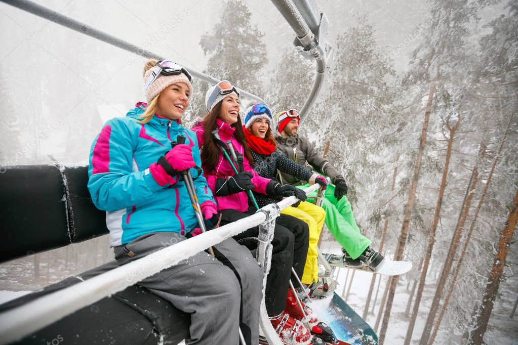 friends enjoying in winter vacations. They ride up ski lift 